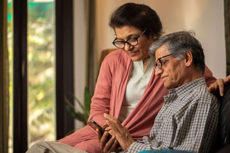 A Hindi man and woman sitting inside looking at a phone.